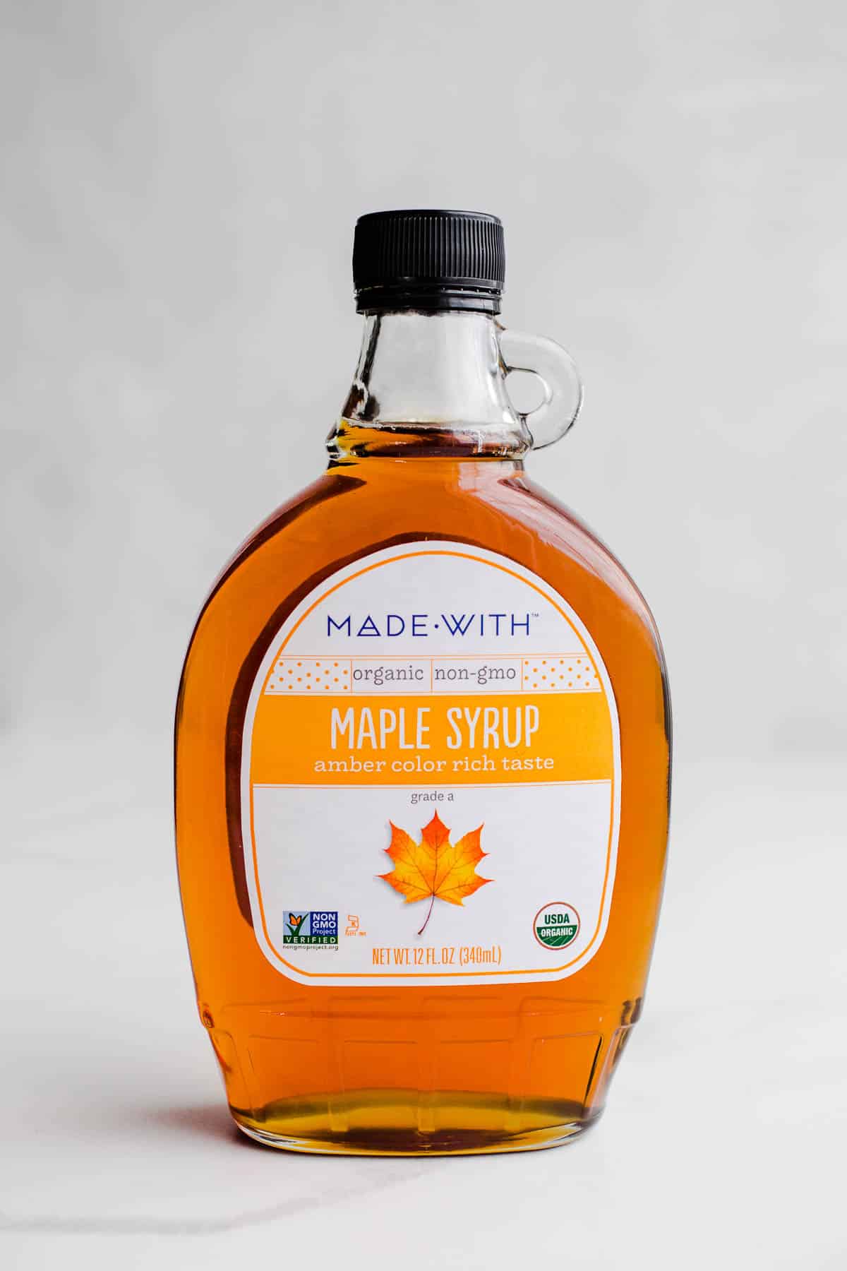 A bottle of 100% pure maple syrup on a marble surface.