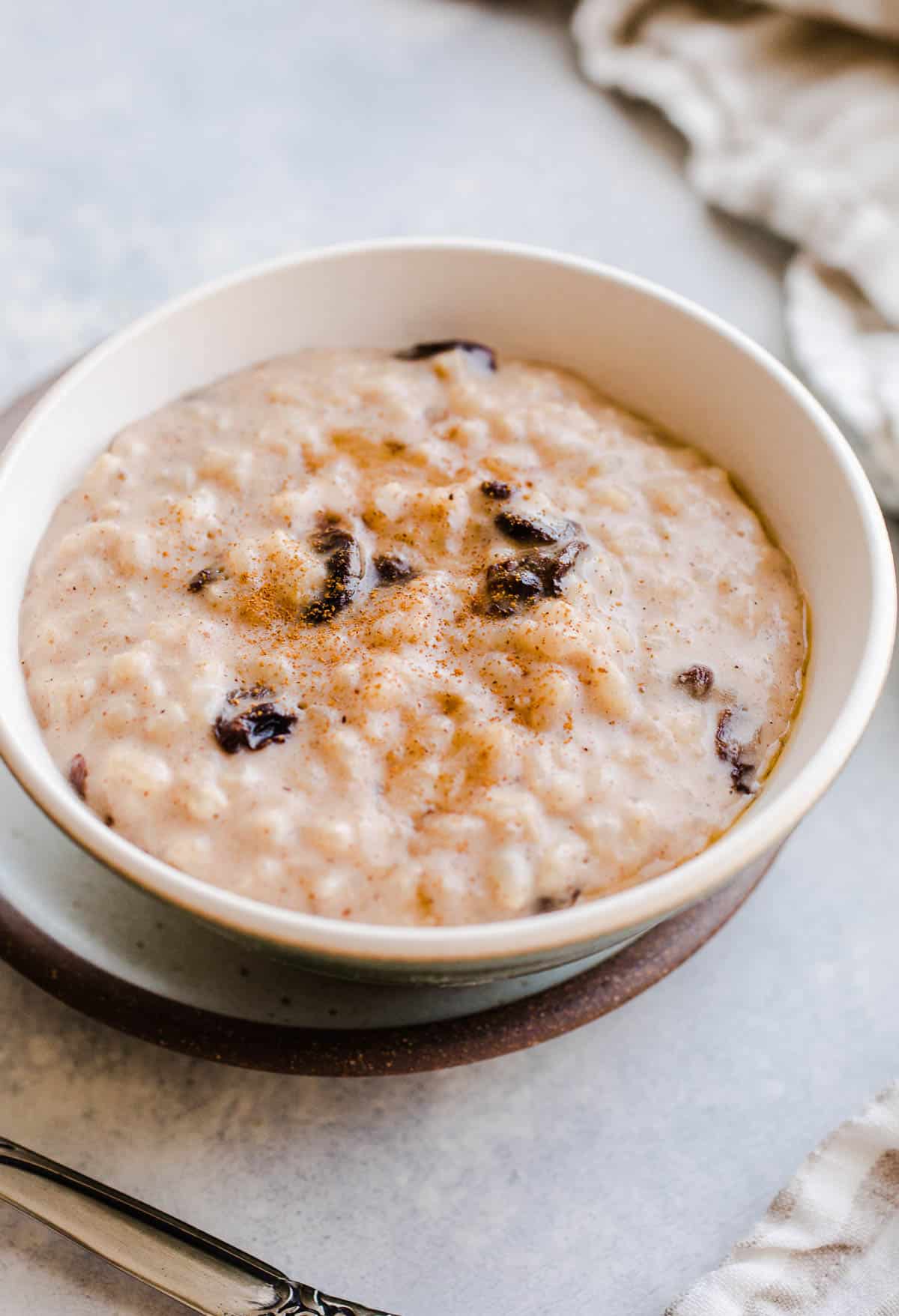 Rice pudding in green bowl with raisins and syrup on top.