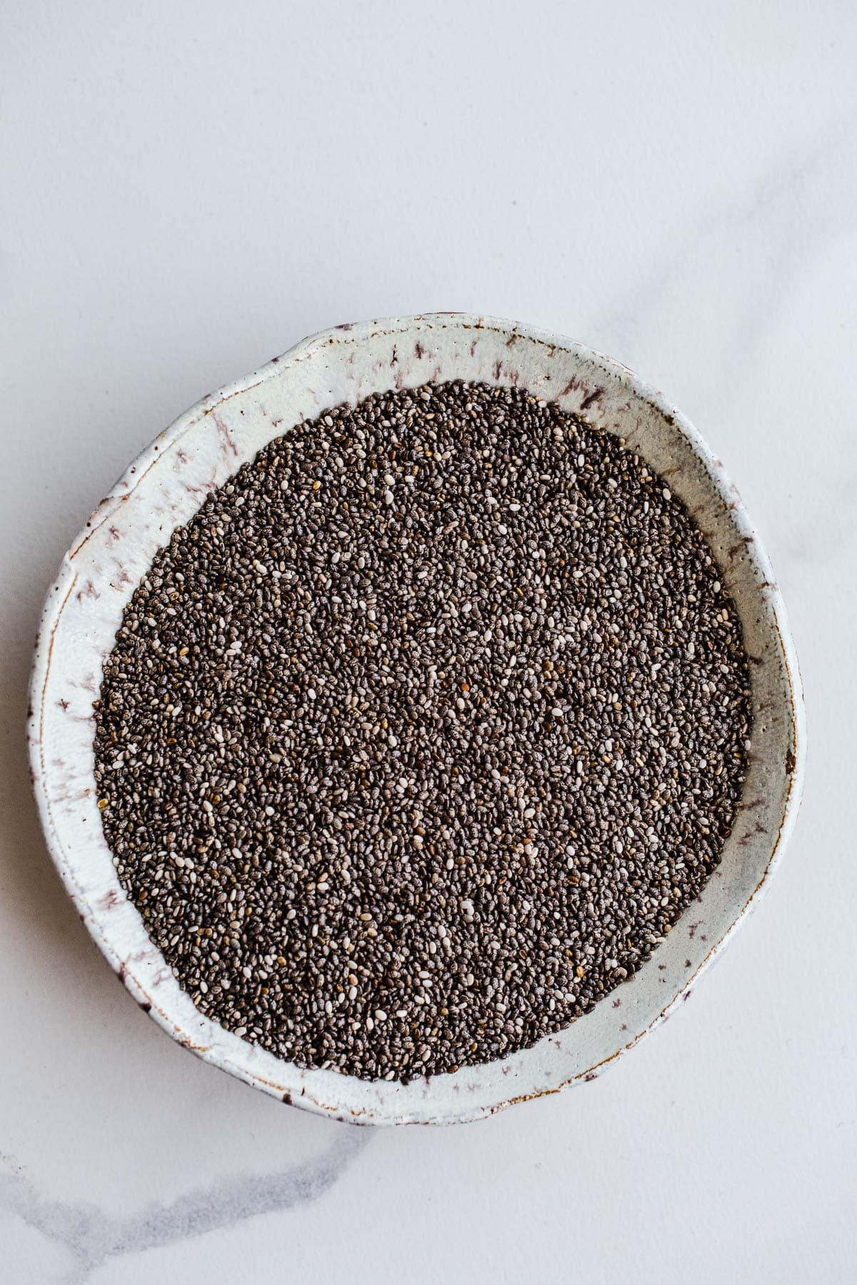 A small white bowl containing black chia seeds.