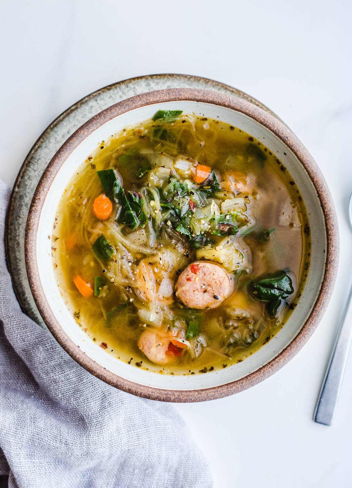 Squash and sausage soup in a rustic bowl.