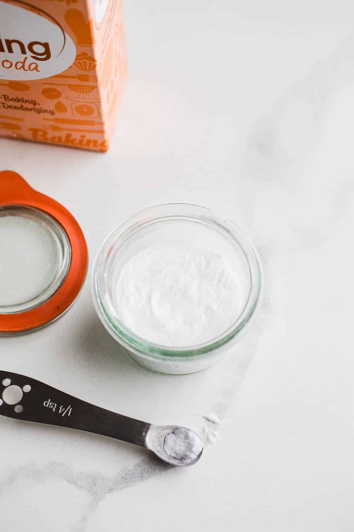 A box and jar of bicarbonate of soda on marble surface.