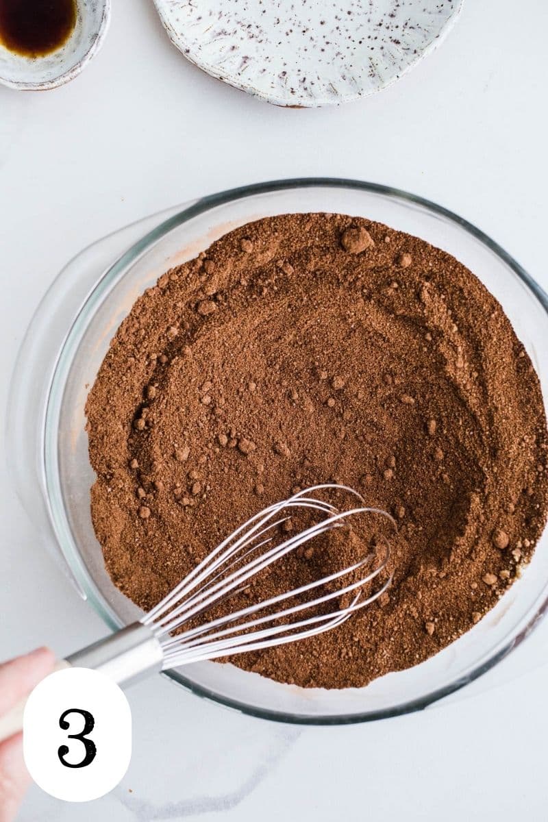Cocoa powder and coconut sugar being whisked in a glass mixing bowl.