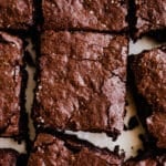 Freshly cut chocolate brownies on white parchment paper.