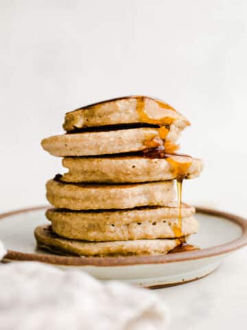 A stack of pancakes on a rustic plate.