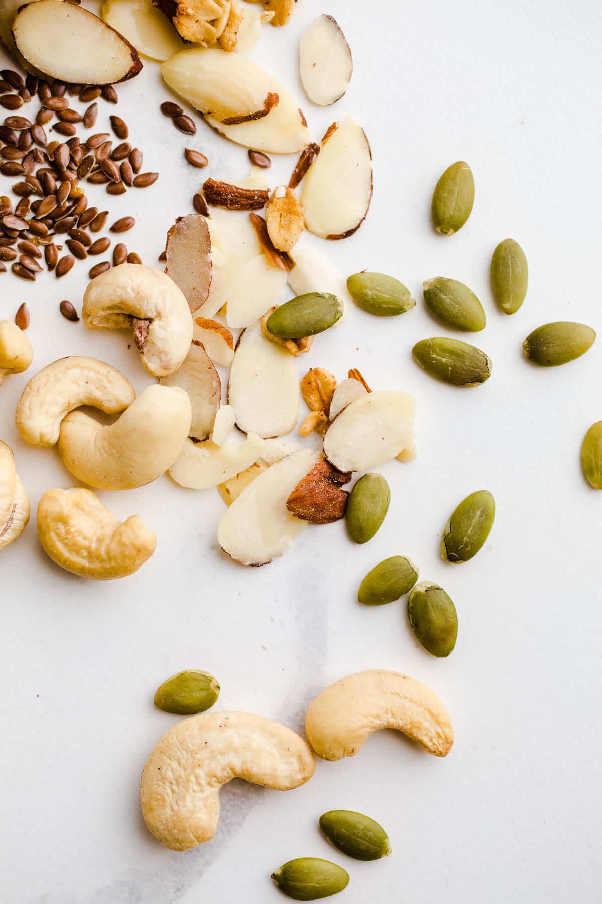 Seeds and nuts spread on a marble surface.