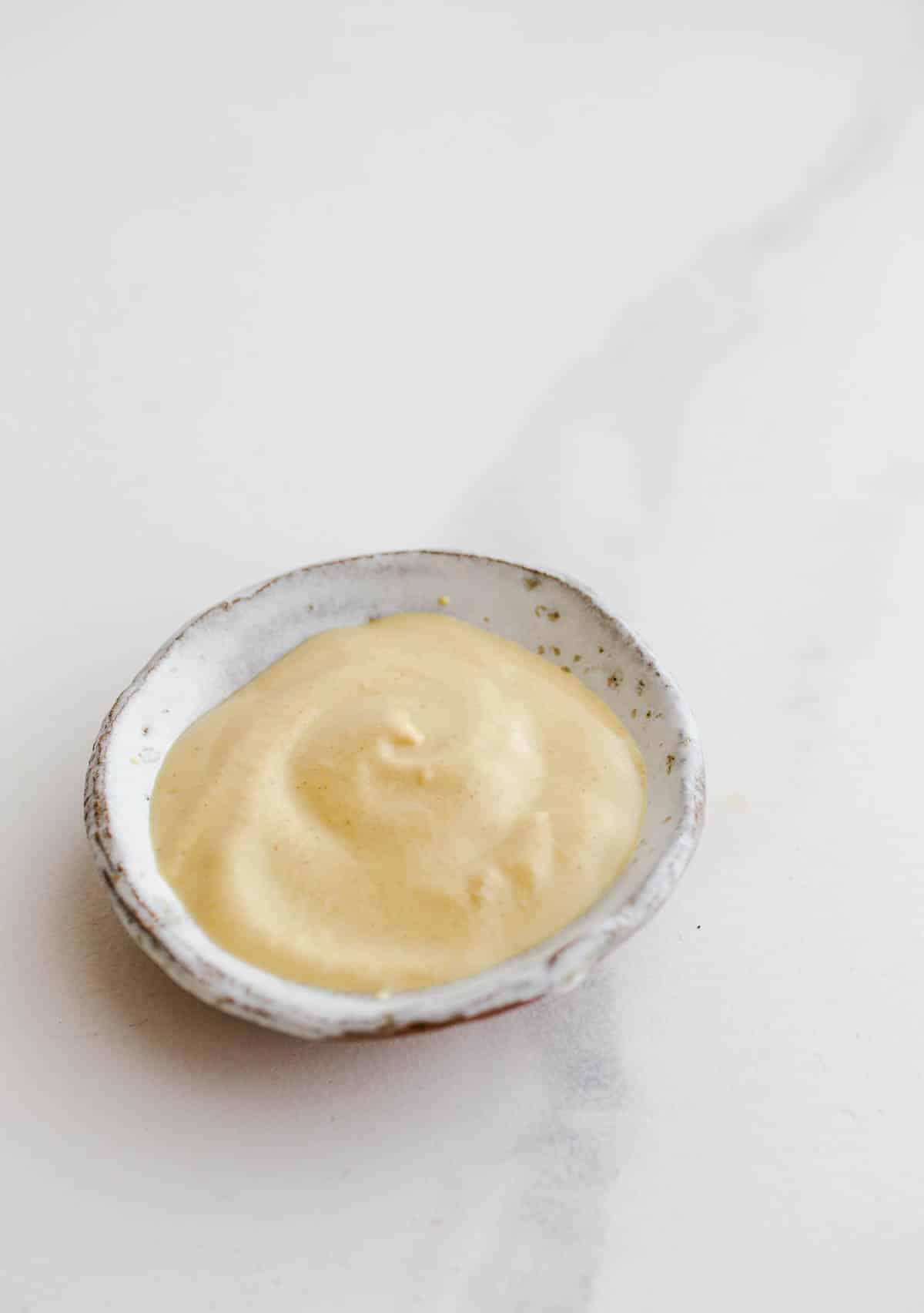 A small white bowl filled with Dijon mustard.