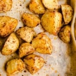 Seasoned potato chunks on a sheet pan.