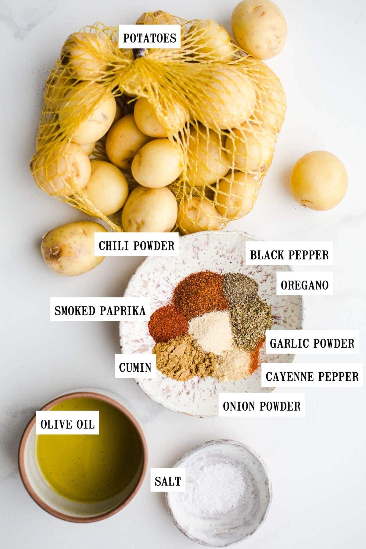 Ingredients to make roasted potatoes on a marble surface.