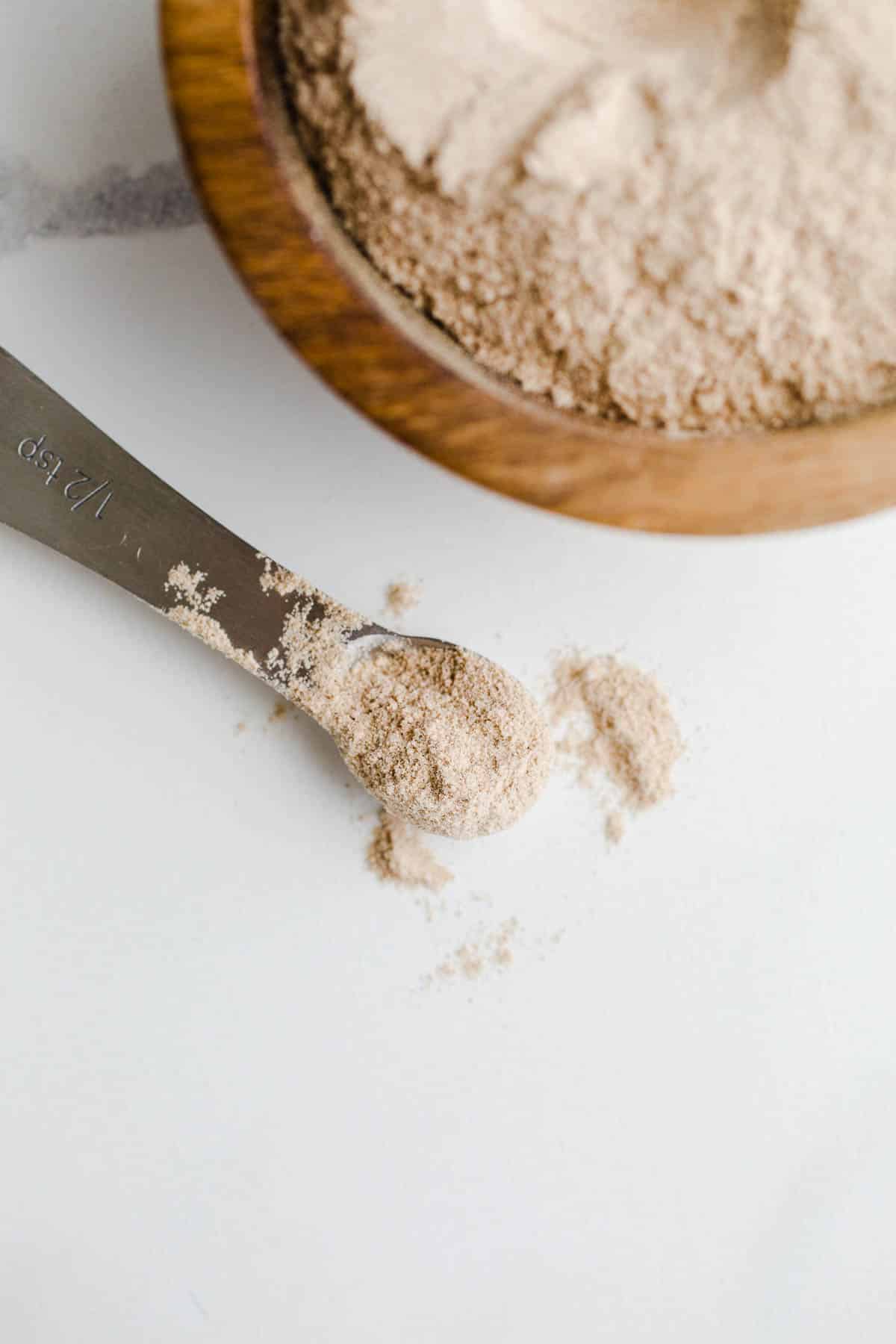 A teaspoon of psyllium husk on a marble surface.