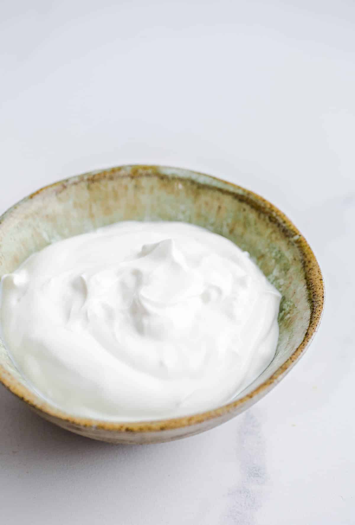 A green bowl with sour cream.