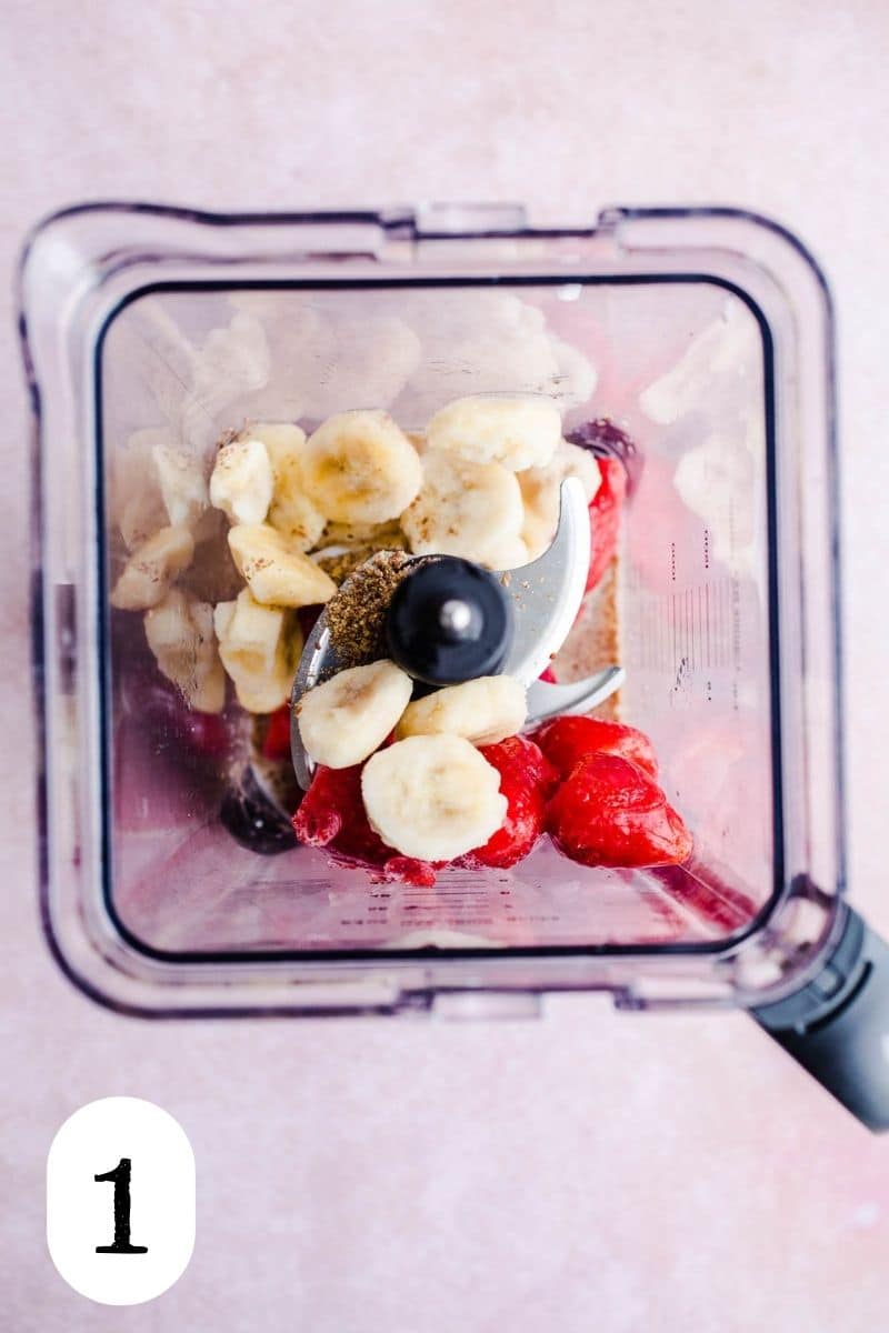 Fruit and milk in the bowl of a blender.