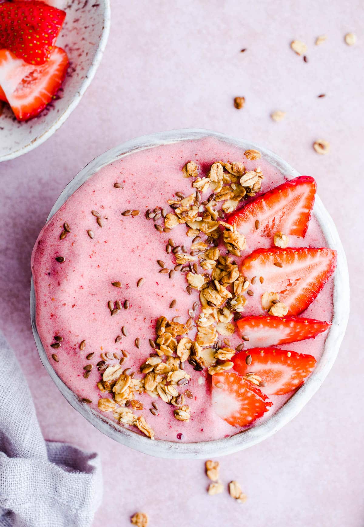 A smoothie bowl topped with granola and strawberries.