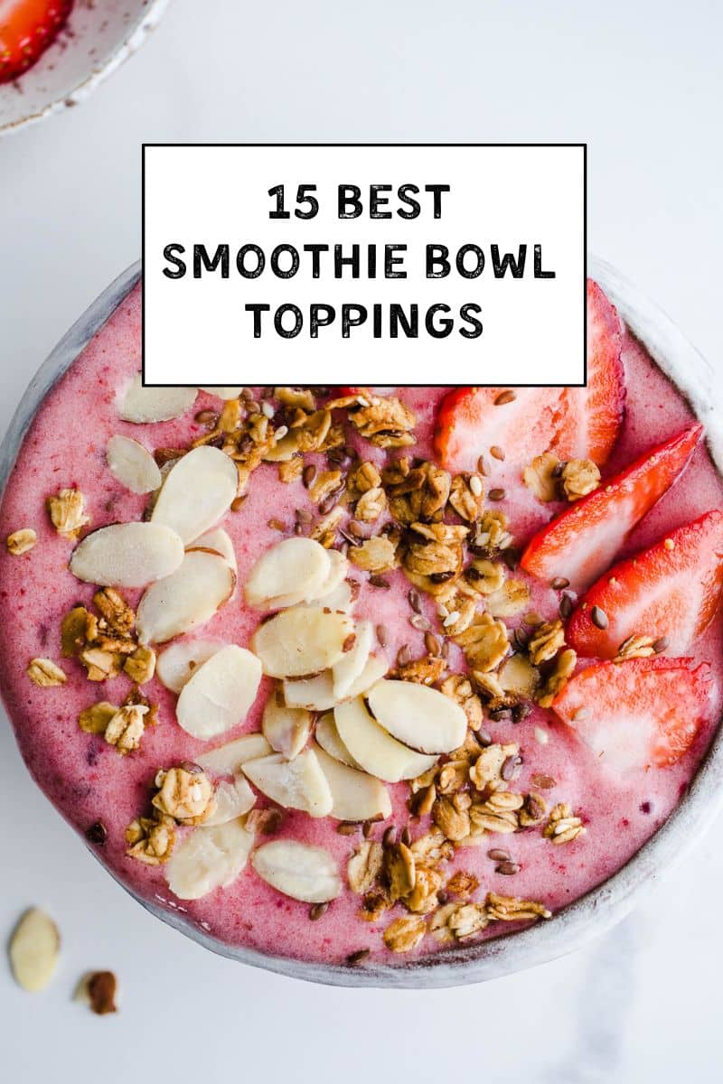 A bowl full of strawberry smoothie topped with granola and nuts.