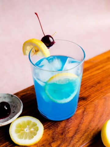 Blue lagoon cocktail with a lemon slice and cherry.