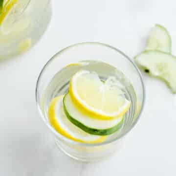 A glass with citrus and cucumber slices.