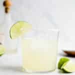 A lime cocktail in a short glass with a lime wedge.