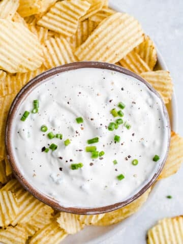 Sour cream dip on a platter with potato chips.