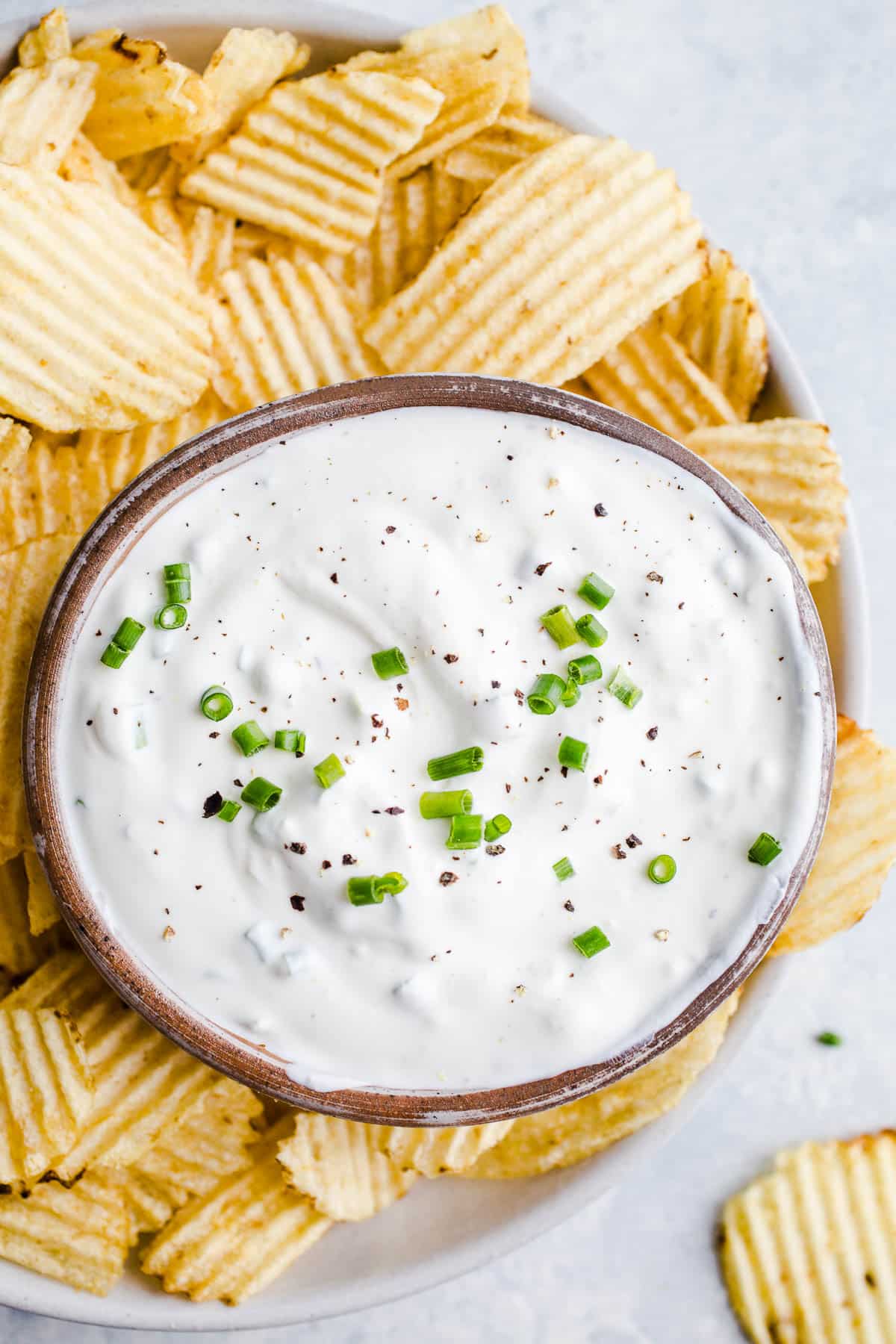 Creamy dip on a platter with potato chips.