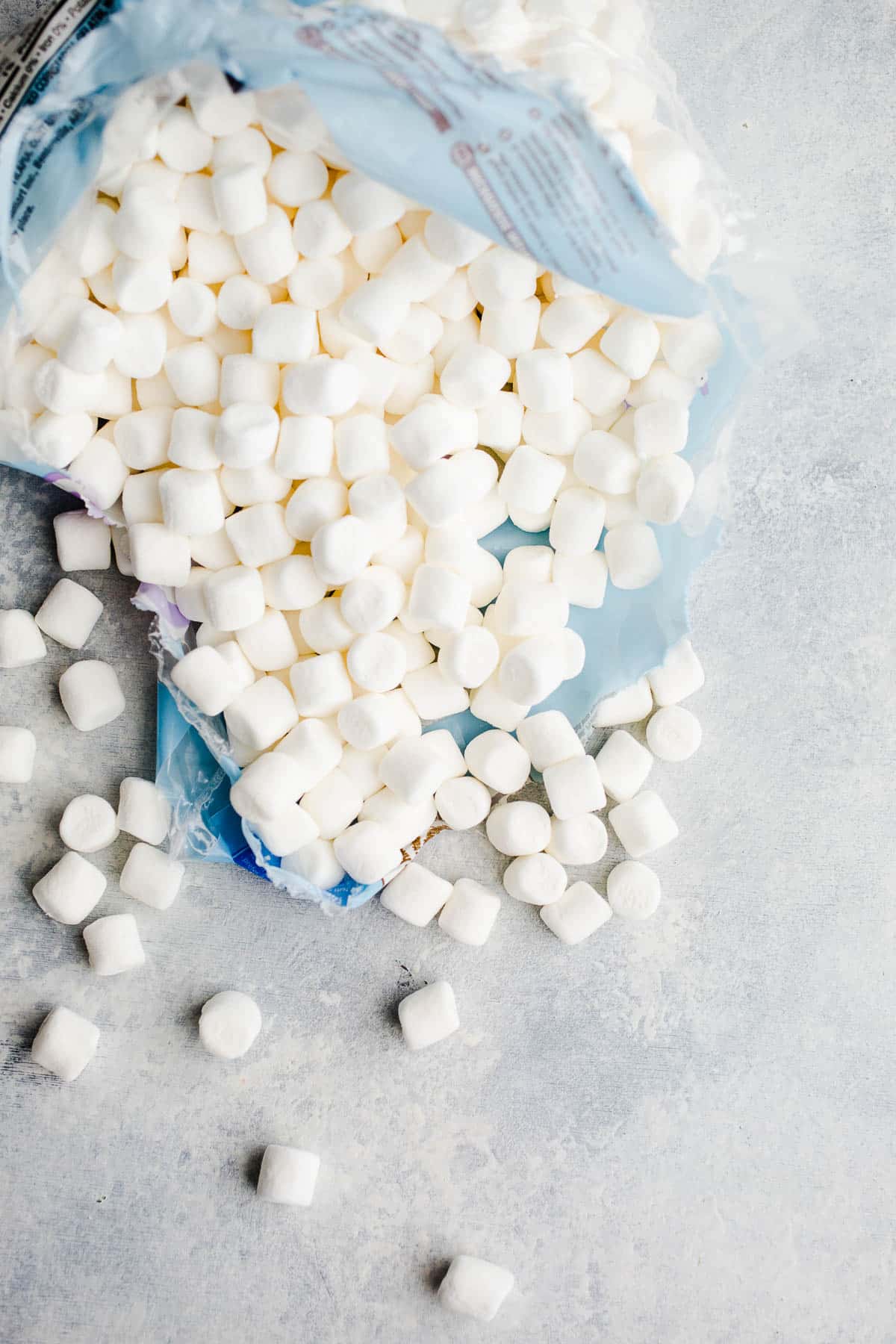 A mini marshmallow bag torn open on a blue surface.