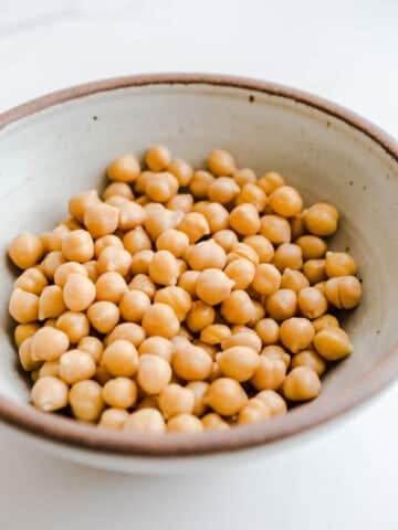 A bowls of chickpeas on a marble surface.