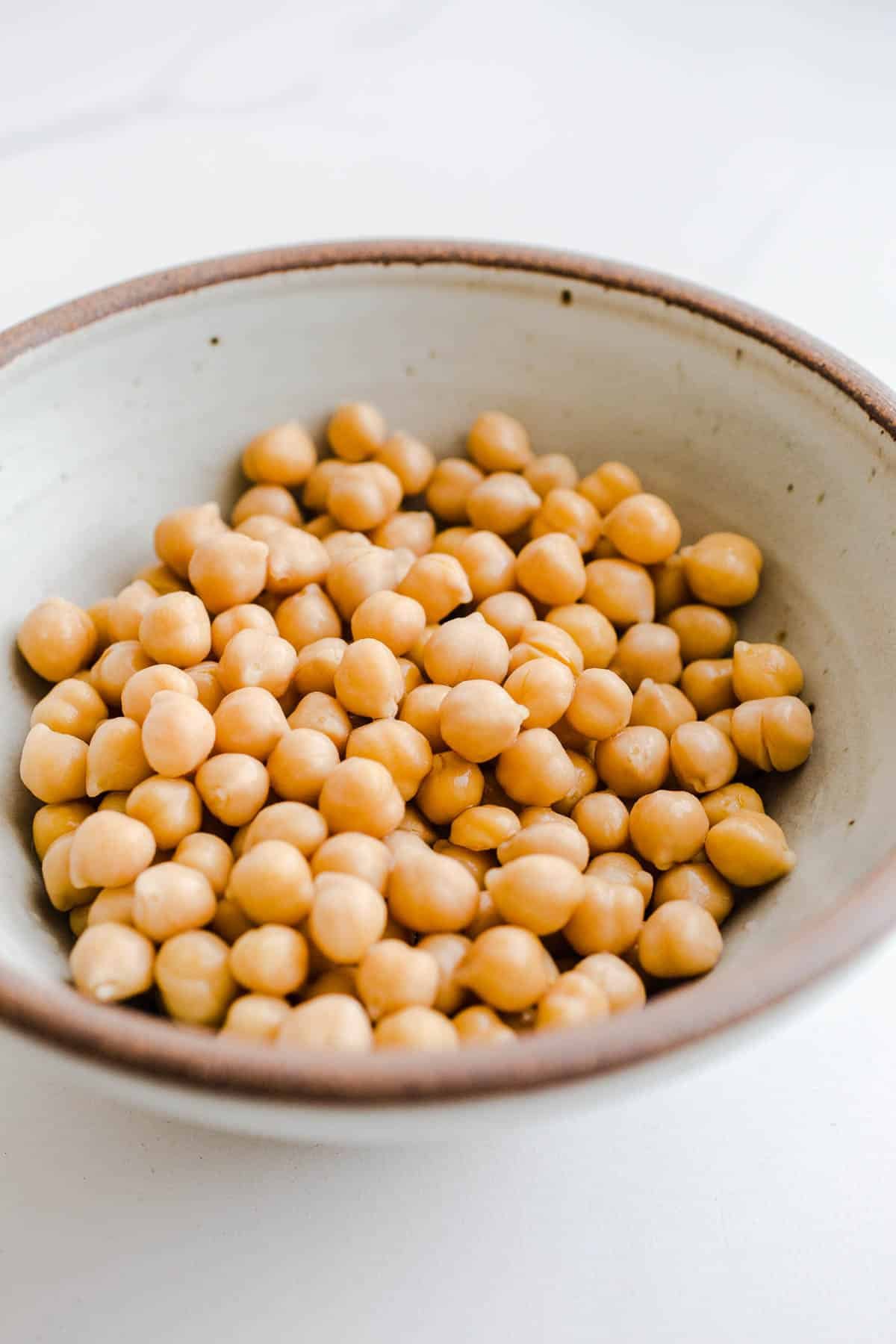 A bowls of chickpeas on a marble surface.