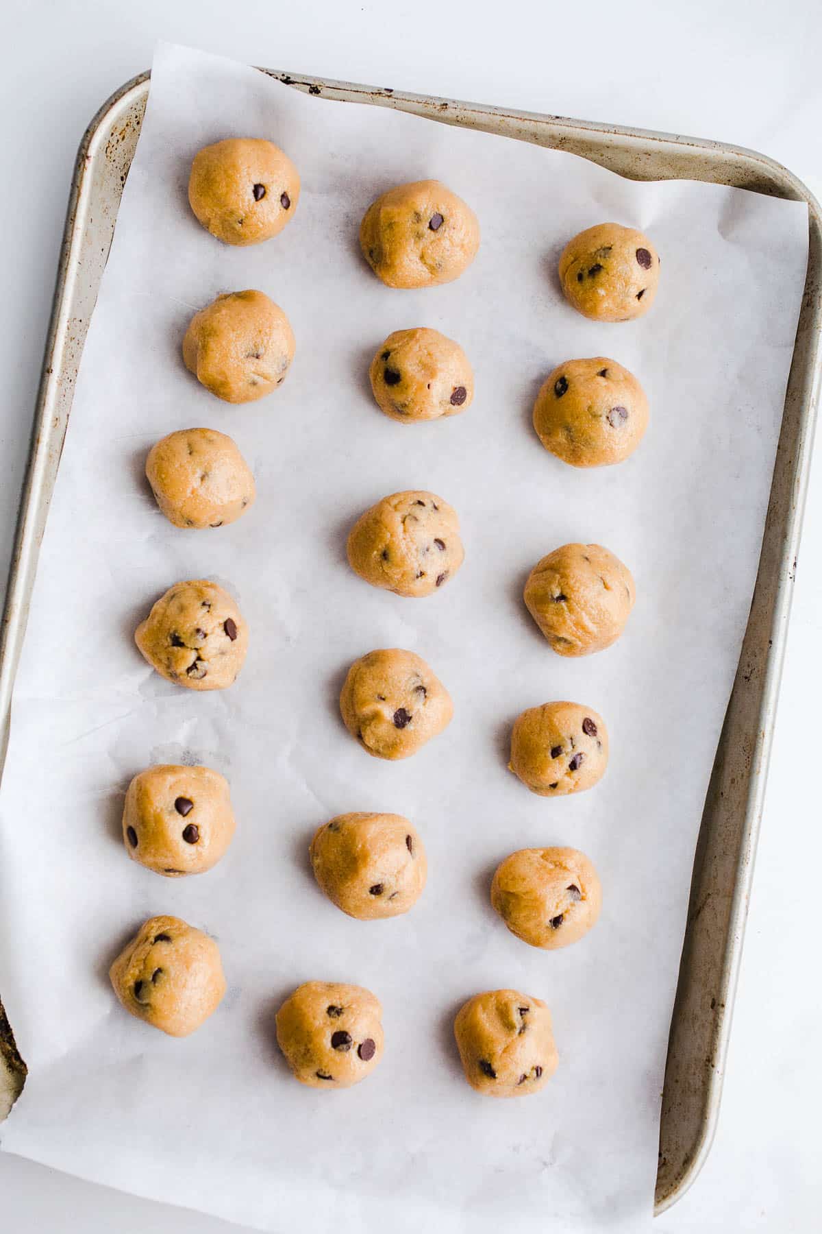 Dough balls with chocolate chips on a baking sheet.