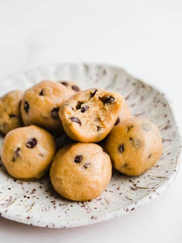 Cookie dough balls on a white speckled plate.