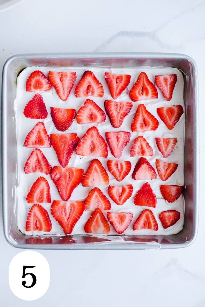 A layer of sliced strawberries in a baking pan.