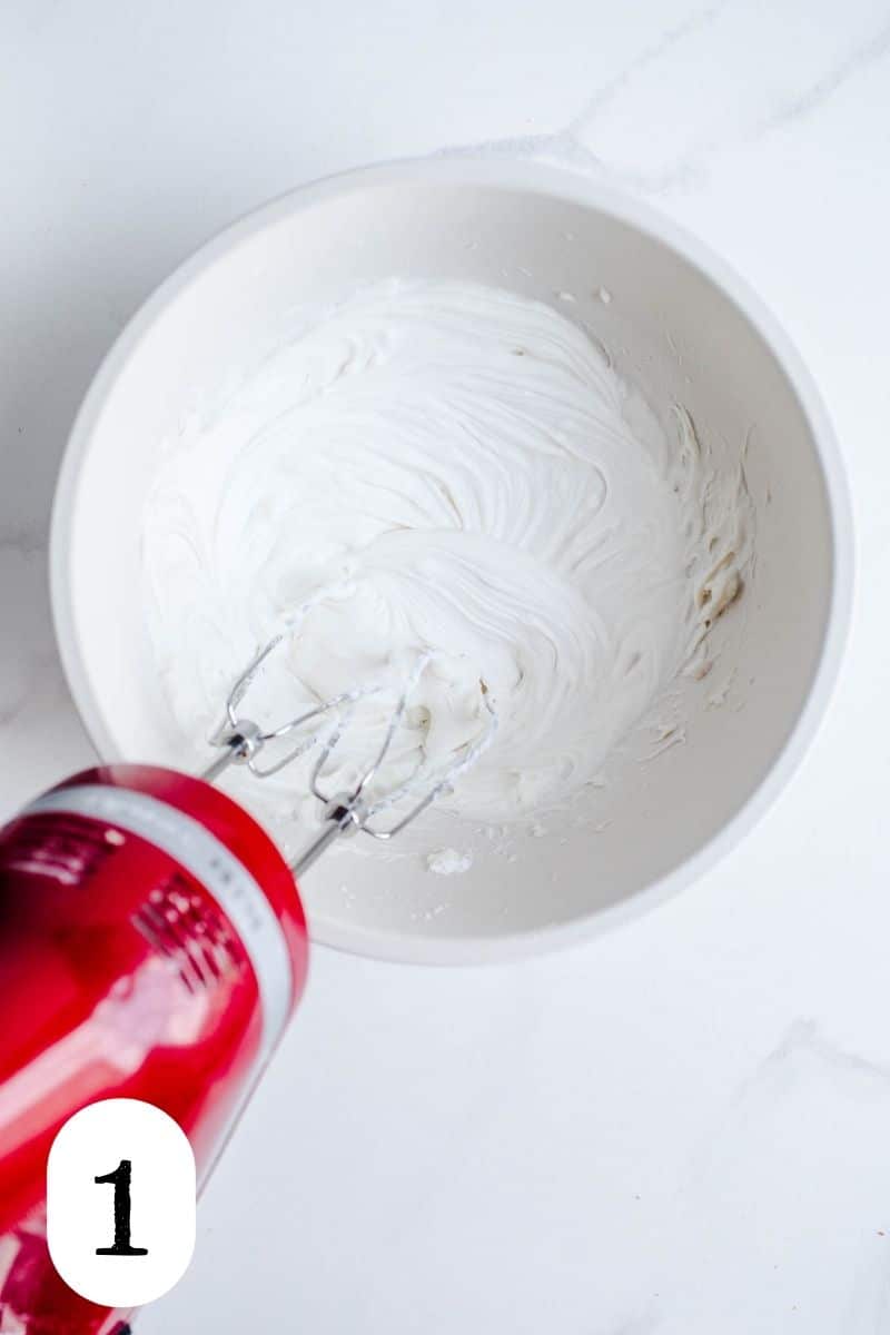 A hand mixer whipping cream in a bowl.