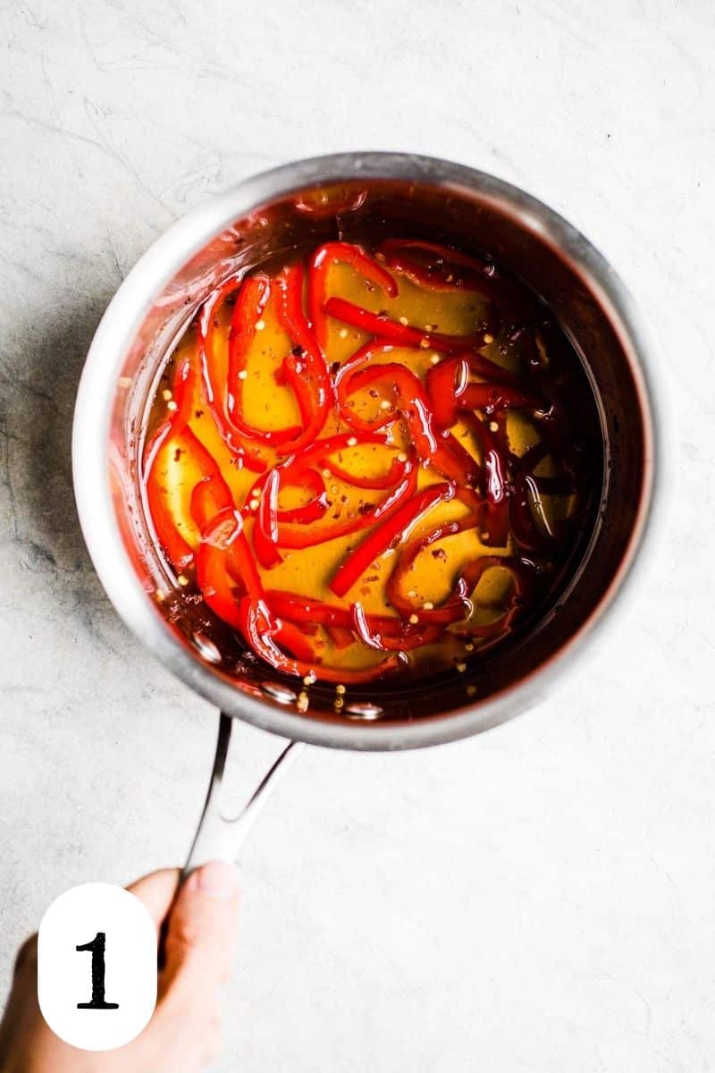 Red peppers in syrup in a saucepan.