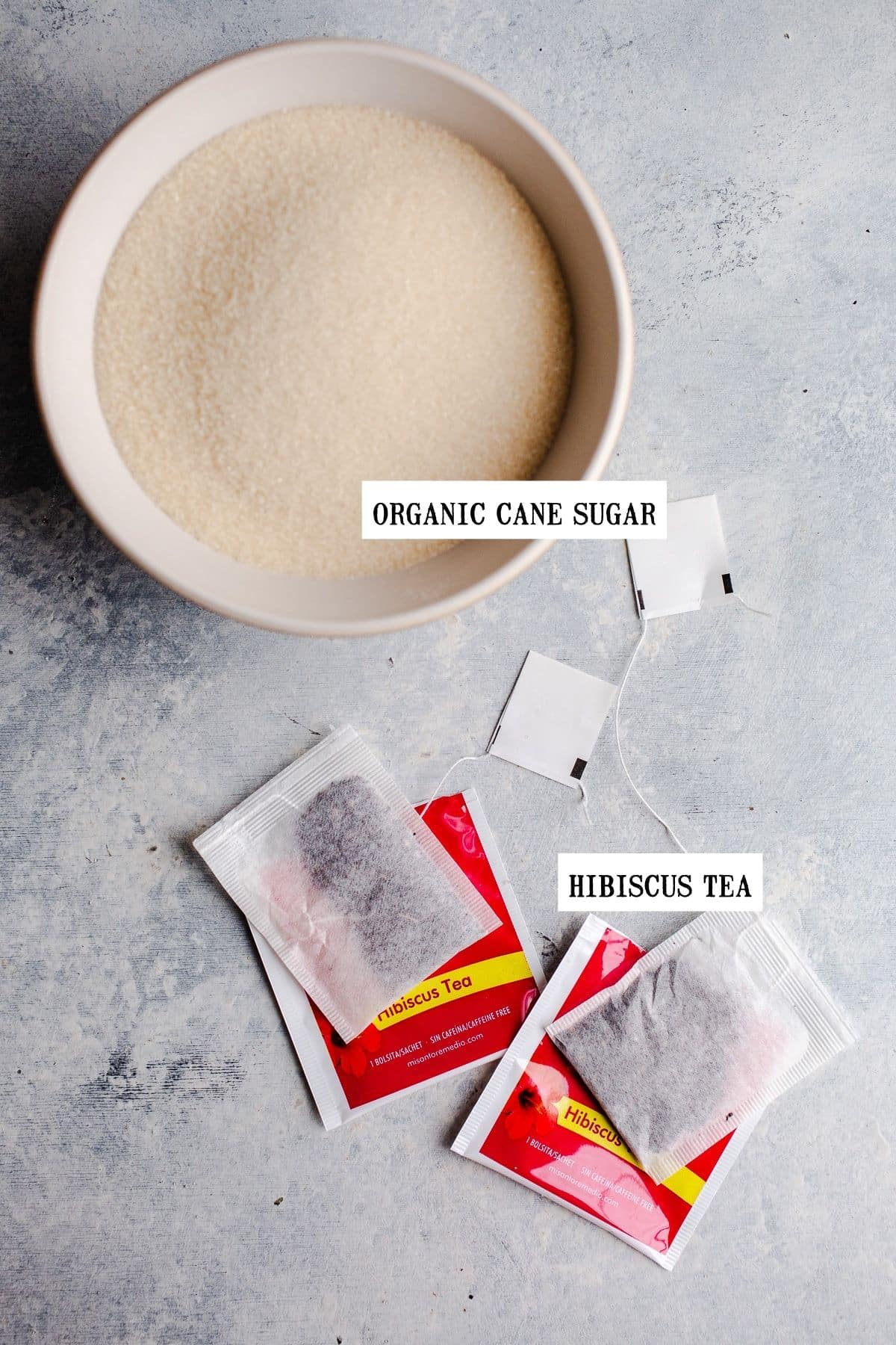 A bowl of sugar next to two tea bags. 
