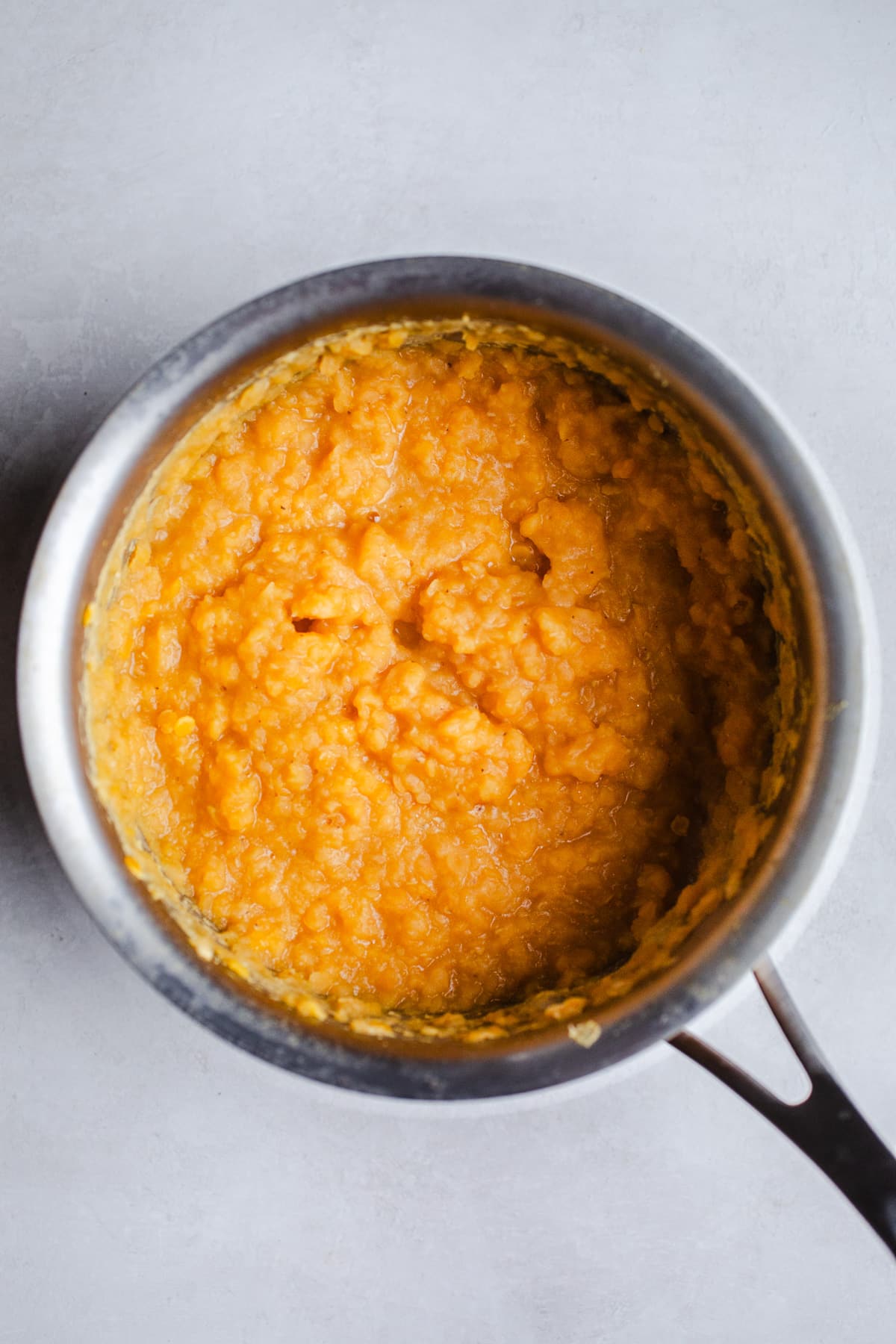 Cooked red lentils in a saucepan.