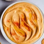 Red lentil hummus in a white bowl.