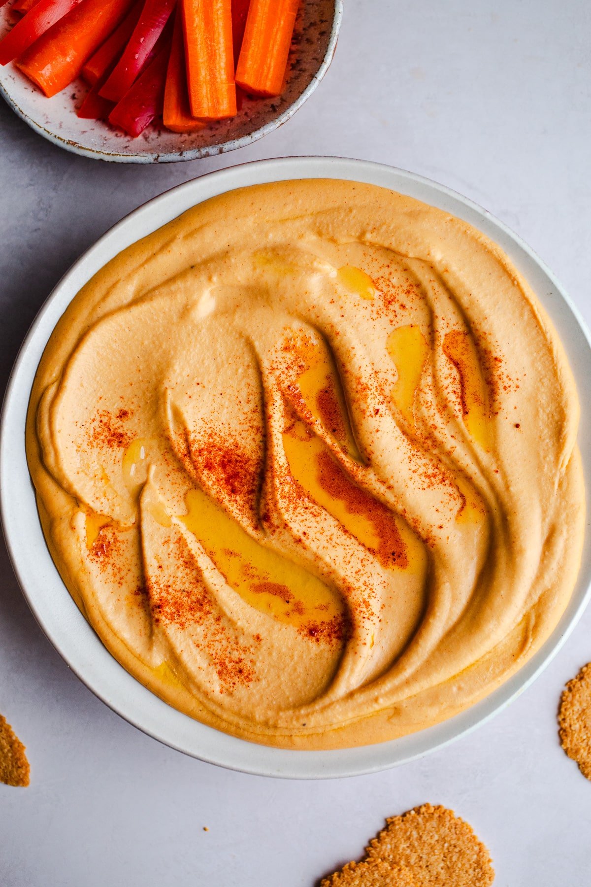 Red lentil hummus in a white bowl. 