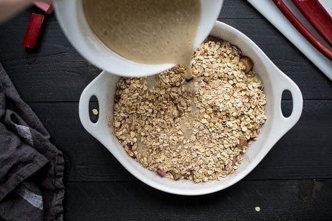 Batter pouring onto oats in a baking dish.