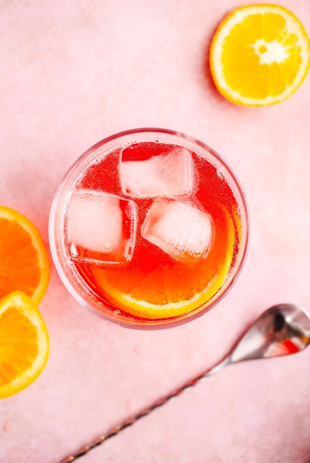 A red drink with an orange slice. 