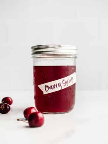 A mason jar filled with cherry syrup.