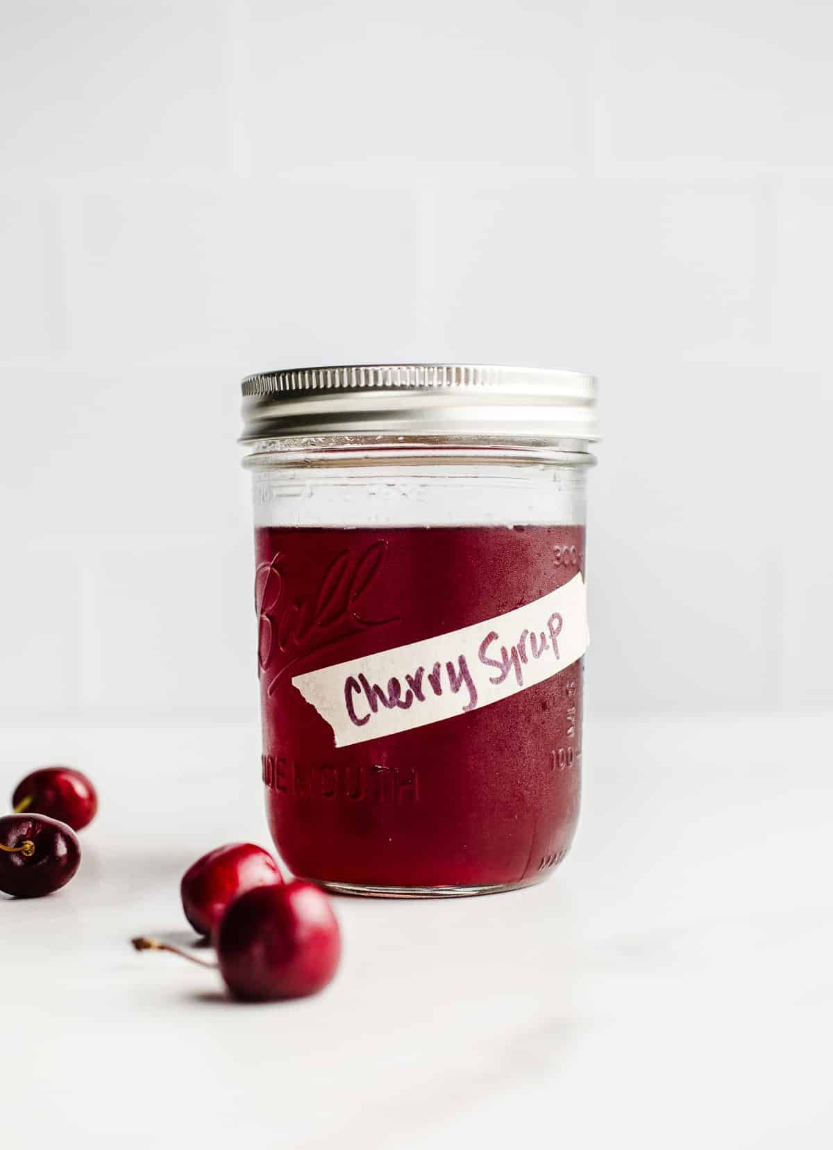 A mason jar filled with cherry syrup.