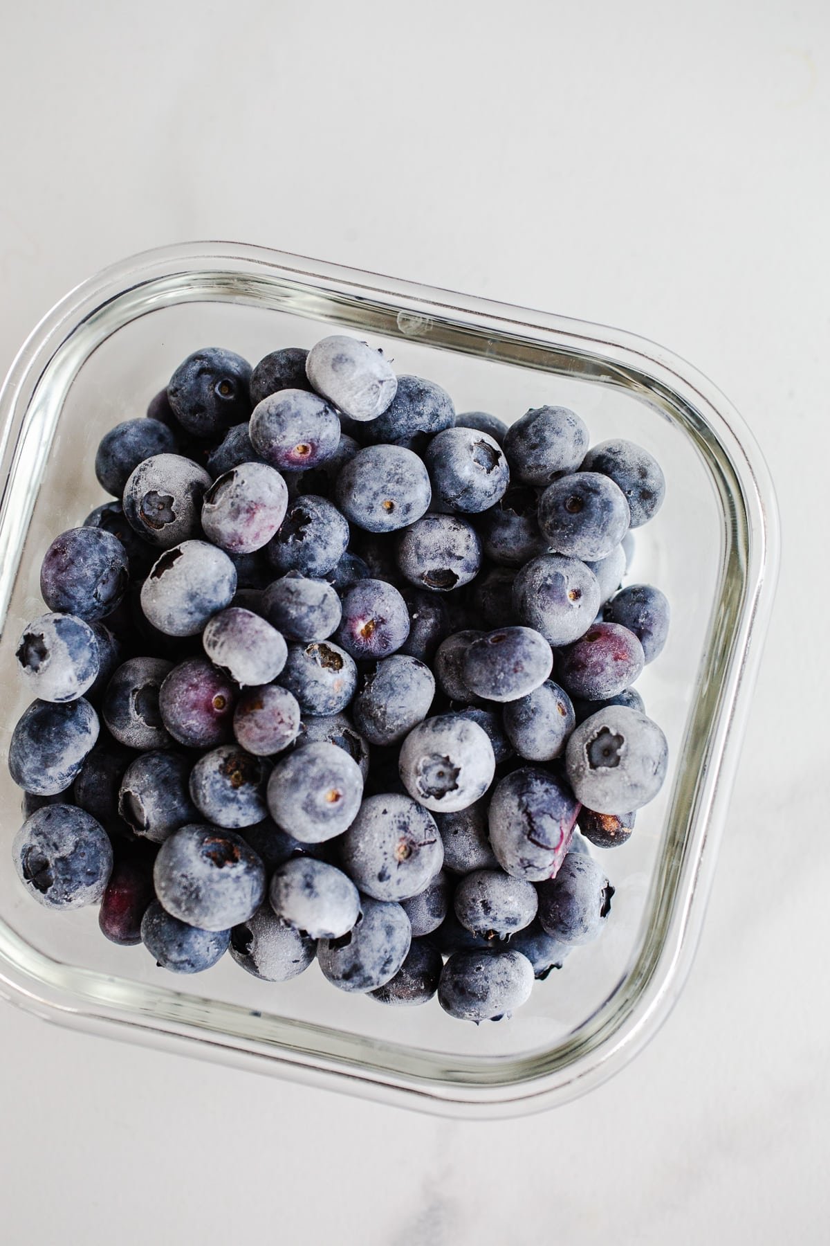 Frozen blueberries in a glass container.