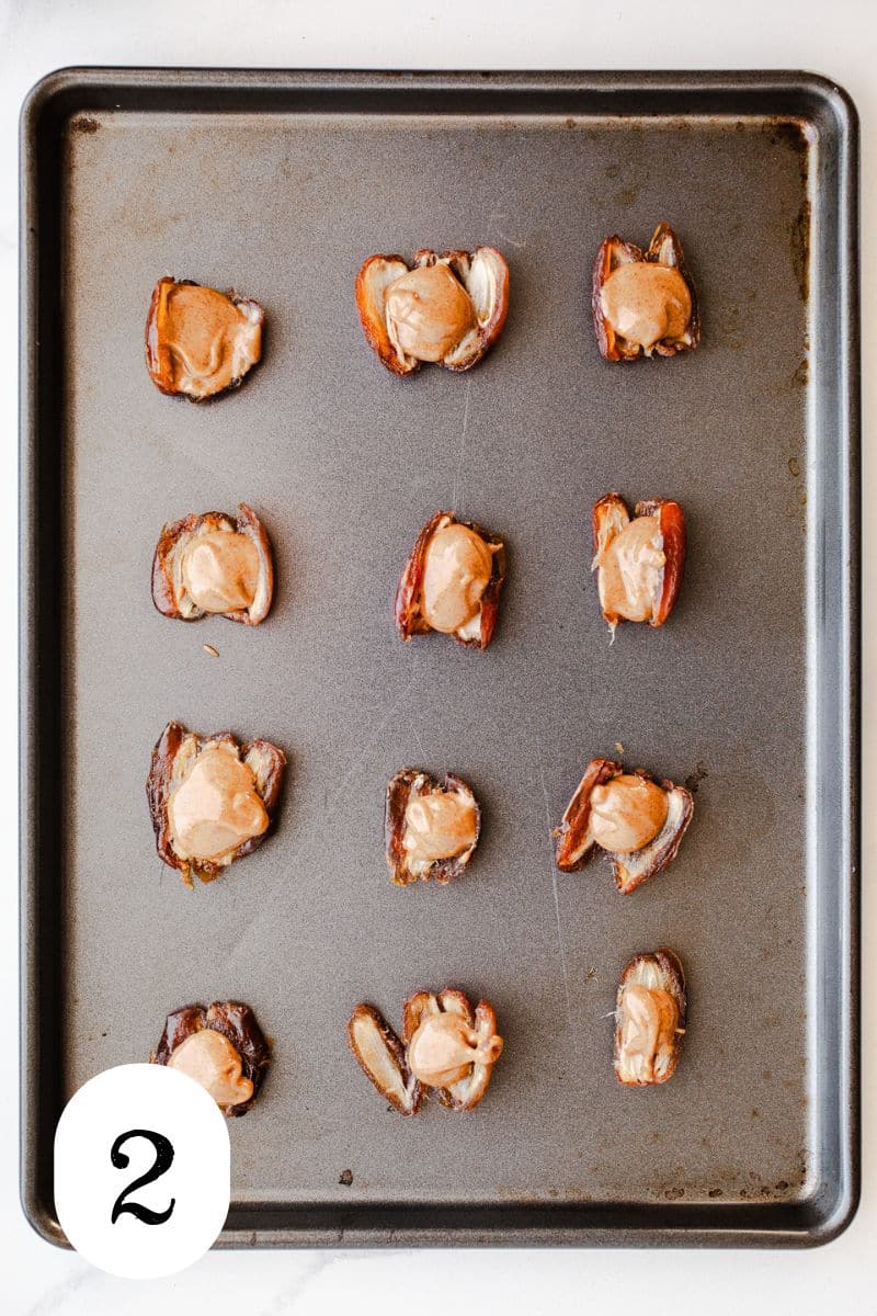 Almond on dates on a baking sheet.