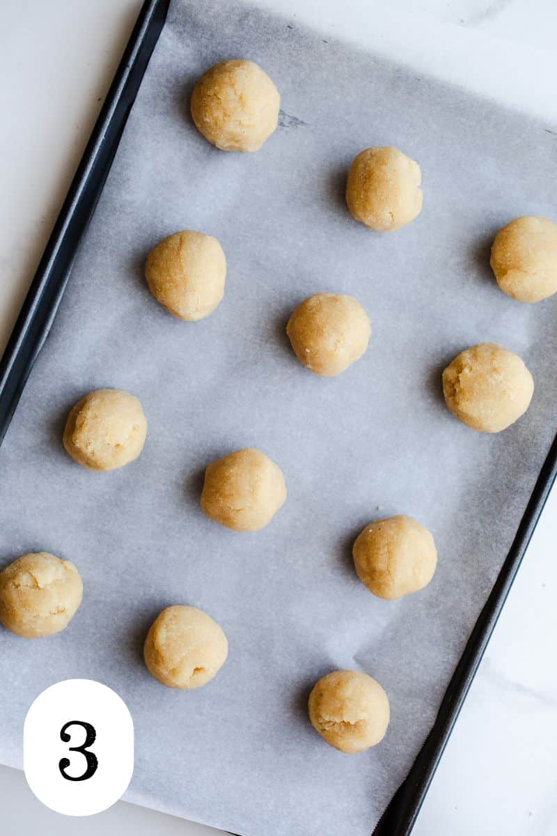 Sugar cookie balls on a baking sheet. 