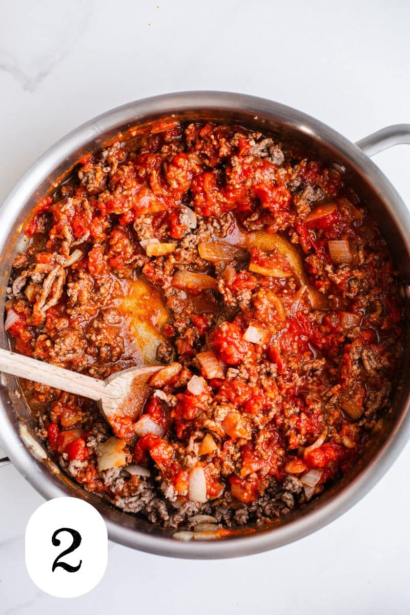 Ground beef and marinara sauce in a skillet. 