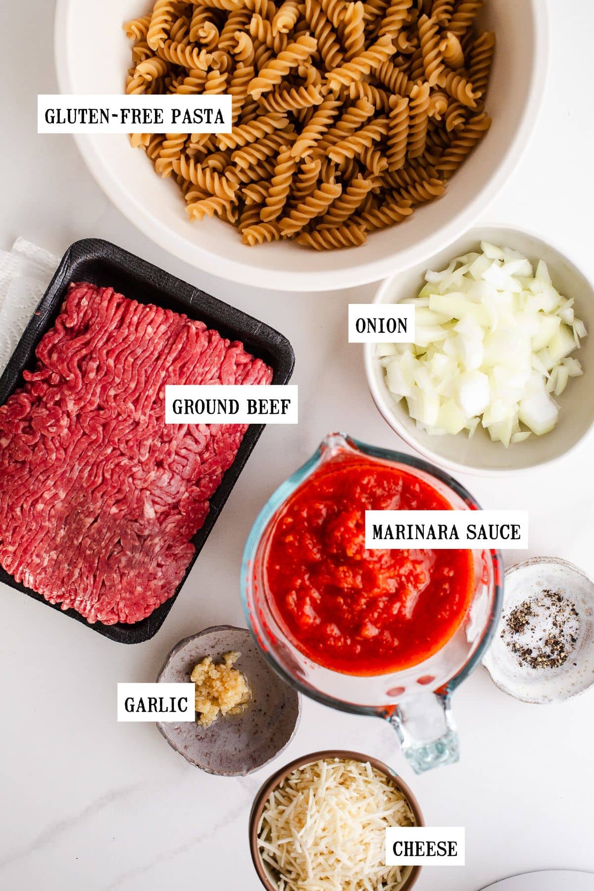 Ingredients to make beef pasta bake on a marble surface. 