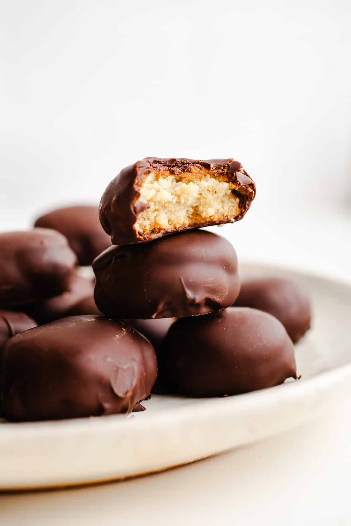 Chocolate covered tagalongs cookies stacked on a plate.