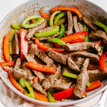 Beef and peppers in a skillet.