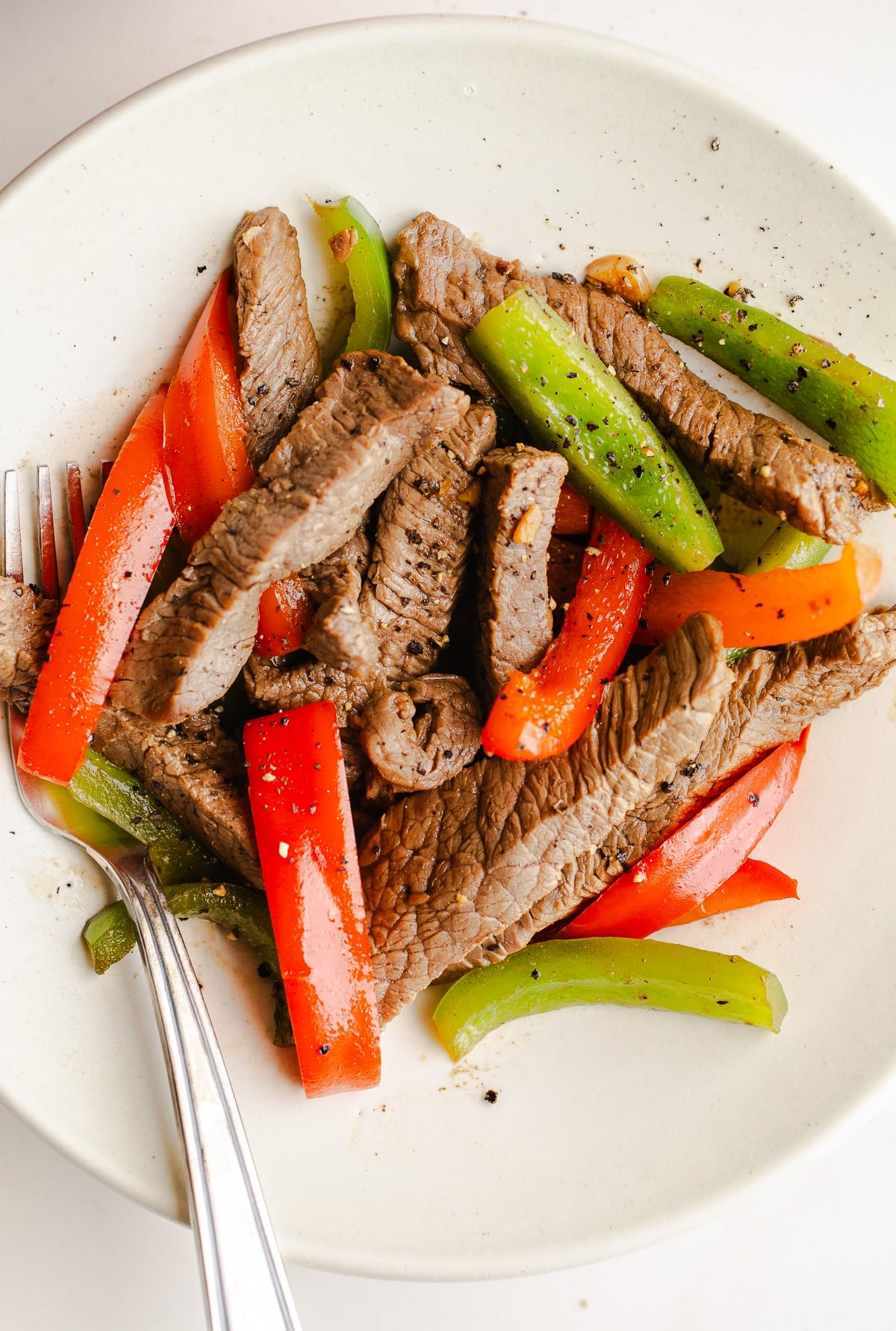 Beef and red and green peppers in a bowl. 