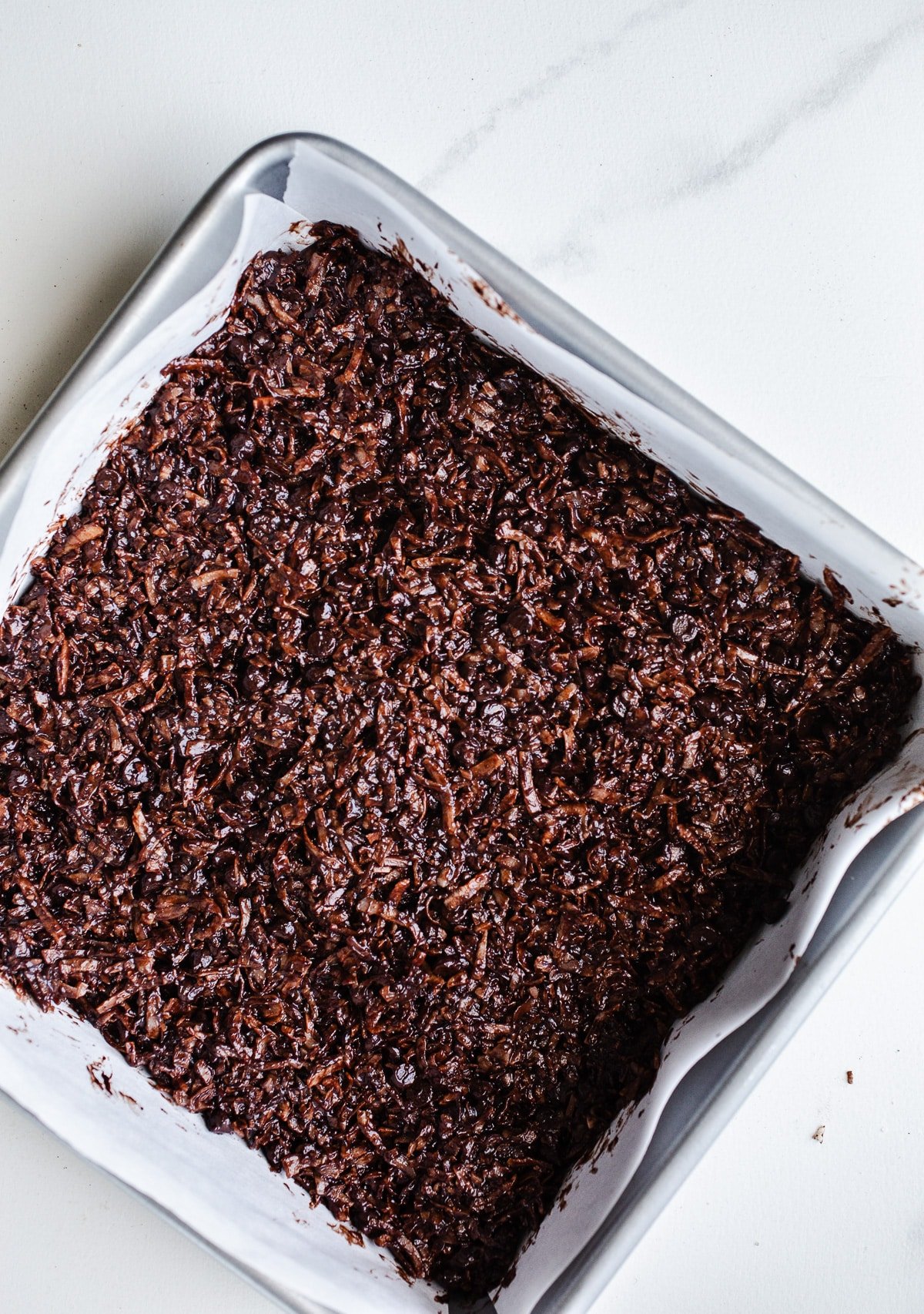 Coconut mixture pressed into a baking pan.