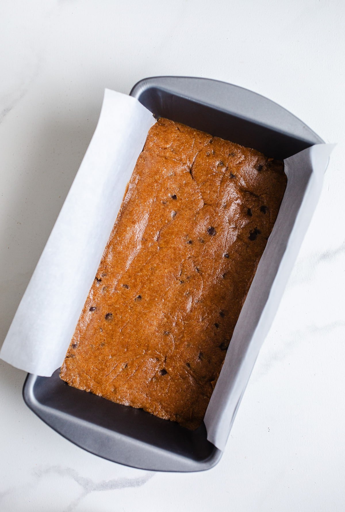 A loaf pan filled with chocolate chip protein dough.
