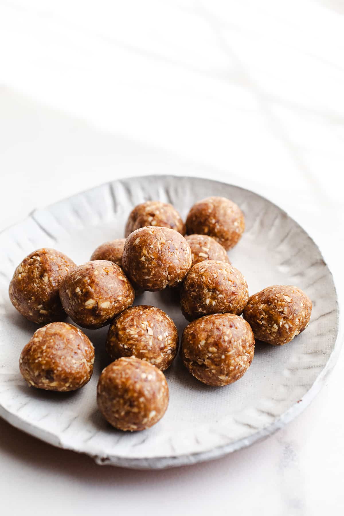 Date caramel balls on a white plate.