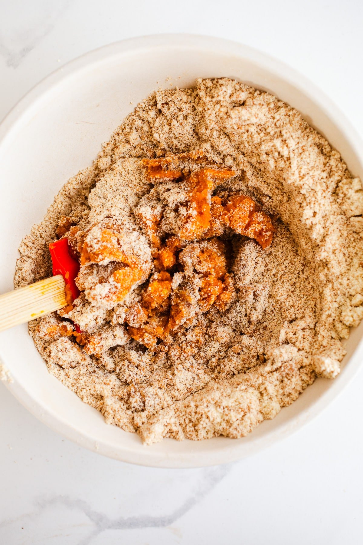 Pumpkin and flour being mixed in a bowl. 
